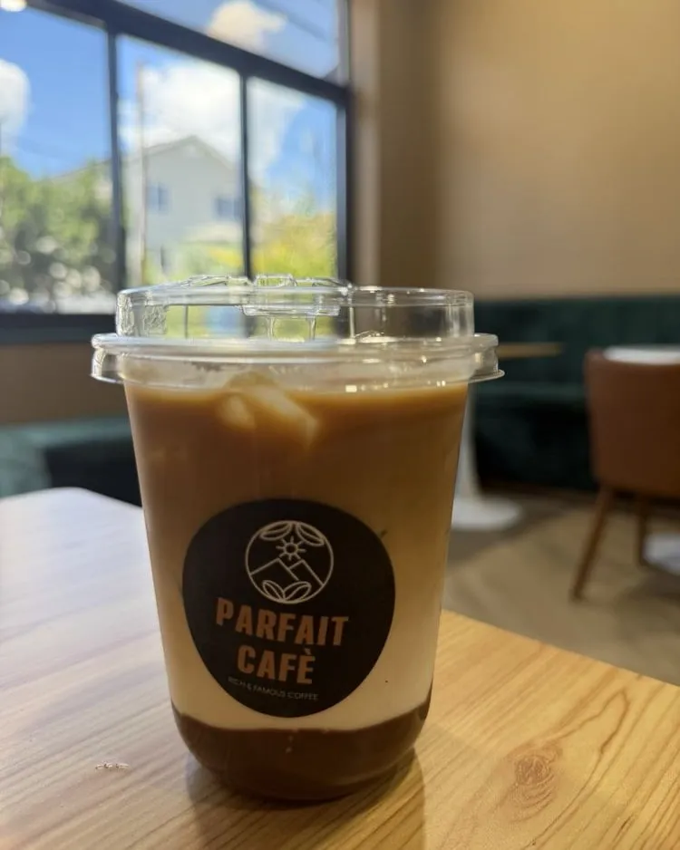 Iced coffee on a wooden table in the window seating at Parfait Café